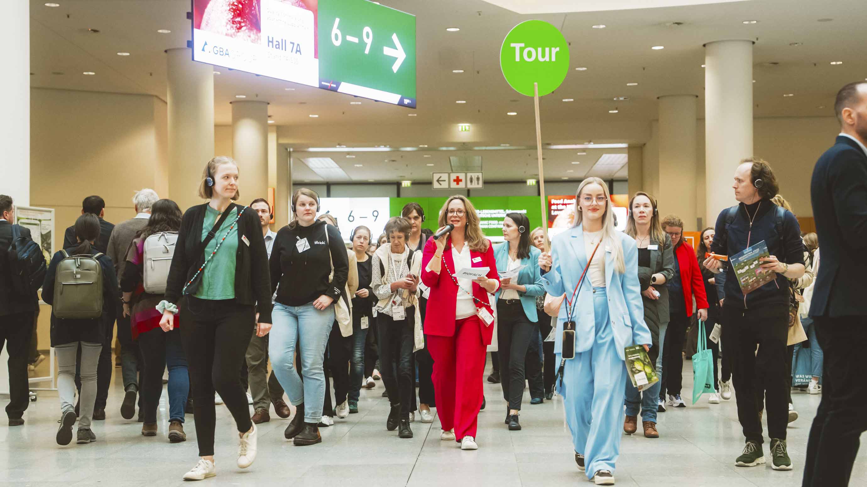 Trade fair visitors on a guided tour walk together to the next booth