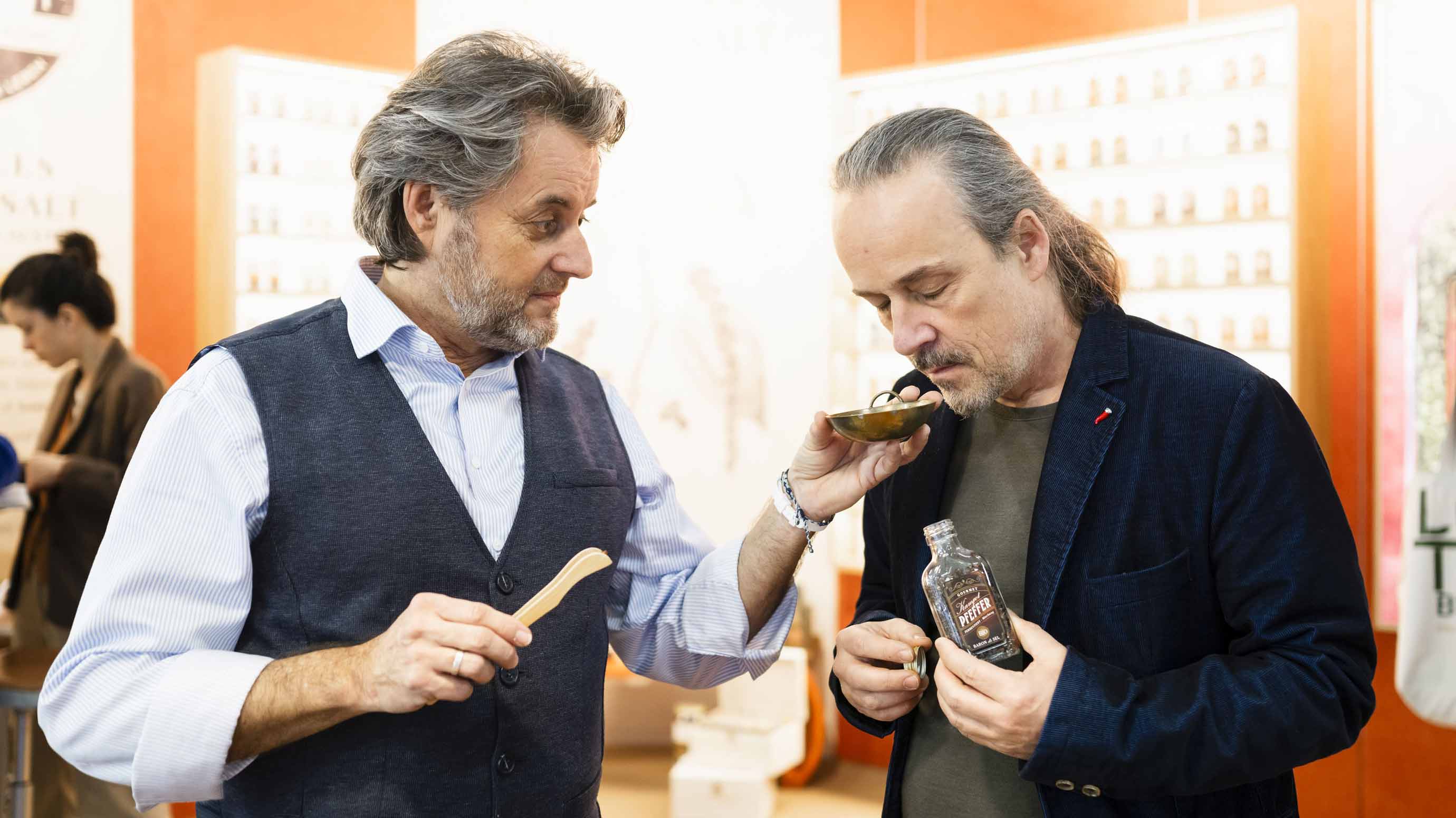 Exhibitor offers a bowl of pepper to a visitor for smelling at booth